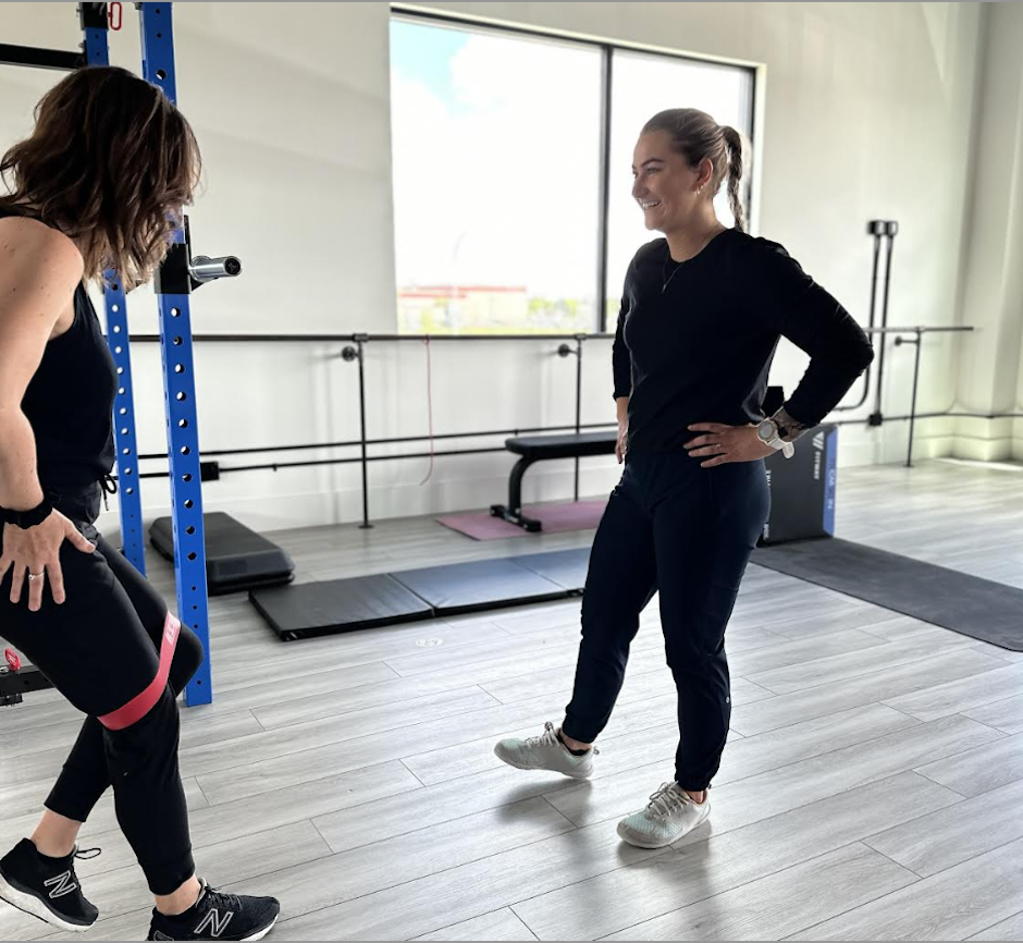 A physiotherapist kicking leg out to side to show a patient the exercise.